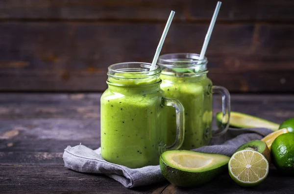 Smoothie verde feito por abacate, limão e kiwi sobre fundo de madeira natural . — Fotografia de Stock