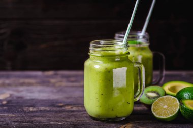 Yeşil smoothie avokado, limon ve doğal ahşap zemin üzerine kivi tarafından yapılan.