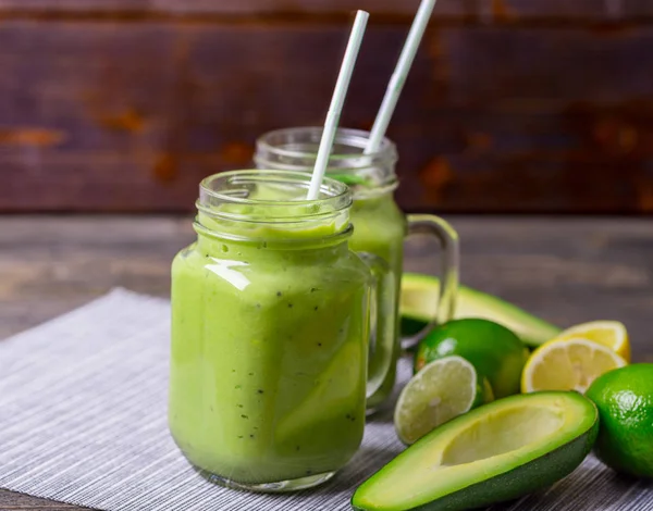 Smoothie verde sobre fundo verde feito por abacate, limão e kiwi . — Fotografia de Stock