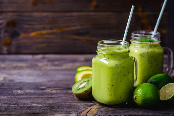 Smoothie verde feito por abacate, limão e kiwi sobre fundo de madeira natural . — Fotografia de Stock