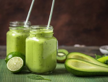 Yeşil smoothie doğal yeşil arka plan üzerinde avokado, limon ve kivi tarafından yapılan.