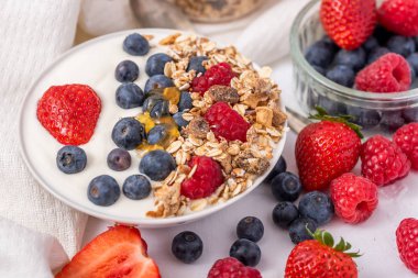 Beyaz arka plan üzerinde yulaf ezmesi ve çilek, yaban mersini ve ahududu ile kase beyaz yoğurt