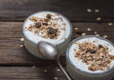 Üstünde yulaf ezmesi ile eski ahşap masada beyaz yoğurt ile iki cam kase.