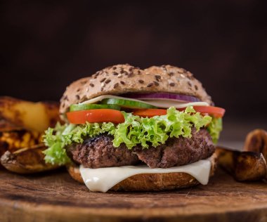 Ev, yeşil salata ve arkasında Amerikan patates ile hamburger yaptı. Ahşap doğal arka plan.