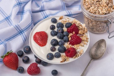 Beyaz arka plan üzerinde yulaf ezmesi ve çilek, yaban mersini ve ahududu ile kase beyaz yoğurt.