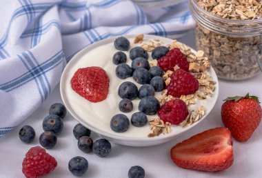 Yulaf ezmesi ve çilek ile kase beyaz yoğurt, üst yaban mersini ve ahududu. 