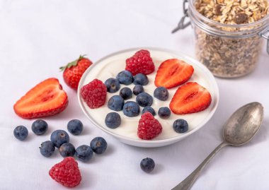 Yulaf ezmesi ve çilek ile kase beyaz yoğurt, üst yaban mersini ve ahududu.
