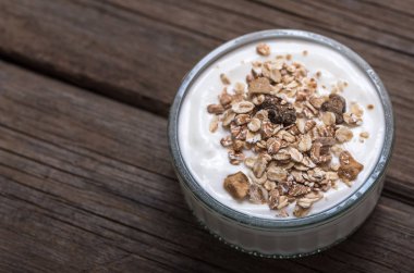 Üzerine yulaf ezmesi ile eski ahşap masada cam kase beyaz yoğurt.