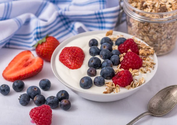 Yogur blanco en un bol con harina de avena y fresas, arándanos y frambuesas en la parte superior . —  Fotos de Stock