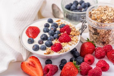 Yulaf ezmesi ve çilek ile kase beyaz yoğurt, üst yaban mersini ve ahududu.