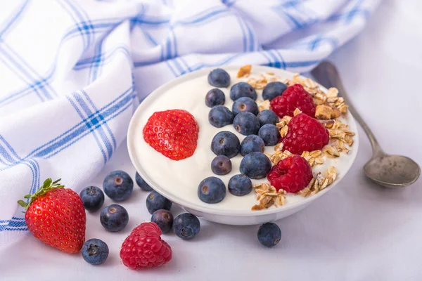 Joghurt fehér tálban eper és áfonya fehér alapon. — Stock Fotó