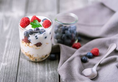 Cam kavanozda beyaz yoğurt ve gri arka planda yabanmersini..