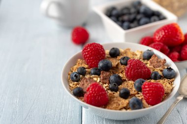 Böğürtlenli granola ve beyaz kaseli ahududu koyu beyaz masa.