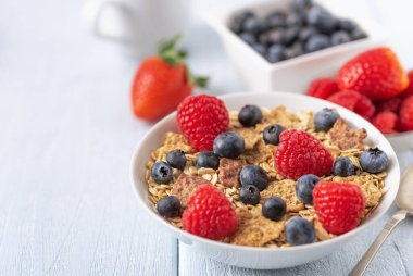 Böğürtlenli granola ve beyaz kaseli ahududu koyu beyaz masa.