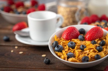 Böğürtlenli mısır gevreği ve ahududu, siyah ahşap masada beyaz kasede..