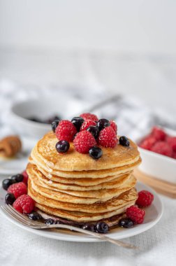 Beyaz tabakta ahududu ve yaban mersinli ev yapımı krepler..