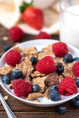 Böğürtlenli granola ve beyaz kaseli ahududu koyu beyaz masa.