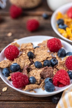 Böğürtlenli granola ve beyaz kaseli ahududu koyu beyaz masa.