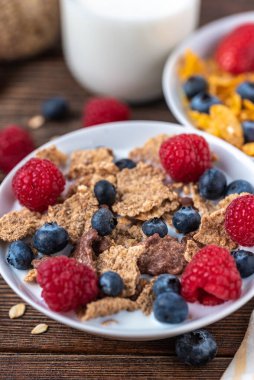 Böğürtlenli granola ve beyaz kaseli ahududu koyu beyaz masa.