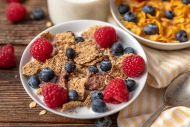 Böğürtlenli granola ve beyaz kaseli ahududu koyu beyaz masa.