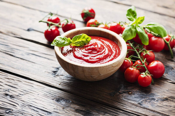 Bowl of tomato sauce and cherry tomatoes on the wooden table, selective focus
