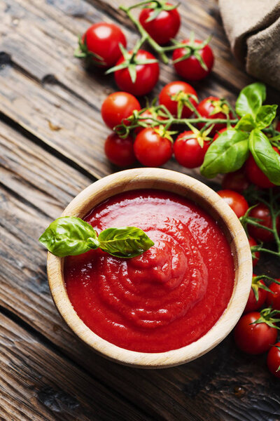 Bowl of tomato sauce and cherry tomatoes on the wooden table, selective focus
