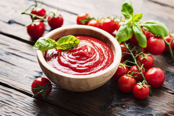 Bowl of tomato sauce and cherry tomatoes on the wooden table, selective focus