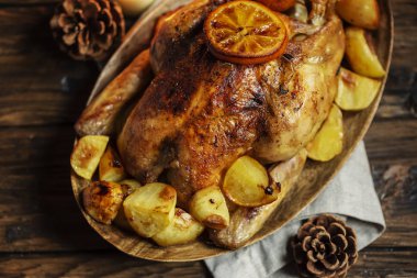 Rustik arka plan üzerinde şenlikli dekorasyon ile kavrulmuş hindi veya tavuk portakal dilimleri ve patates plaka Noel yemeği servis.