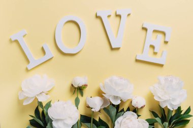 Sarı arka planda beyaz zarif şakayık ve ahşap harfler. Tebrik kartı kavramı, aşk kavramı, üst görünüm