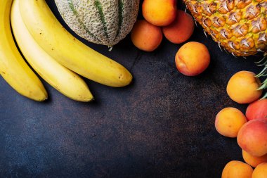 Sağlıklı vejetaryen yemeği kavramı. Ananas, muz, kayısı, kavun, siyah arka planda avokado. En üst görüntü