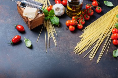 İtalyan yemeği kavramı: spagetti, domates, fesleğen, sarımsak, peynir ve siyah masadaki zeytinyağı. Kopyalama alanı olan üst görünüm