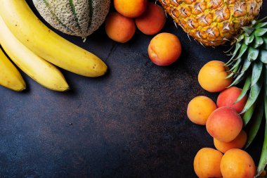 Sağlıklı vejetaryen yemeği kavramı. Ananas, muz, kayısı, kavun, siyah arka planda avokado. En üst görüntü