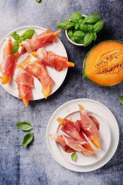 Tatlı kavun ve koyu arkaplanlı jambonlu yaz aperatifi. Kopyalama alanı olan en üst görüntü