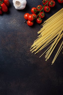 İtalyan makarnası pişirmek için gerekenler: spagetti, domates ve siyah masada sarımsak. Fotokopi alanı olan en üst görüntü
