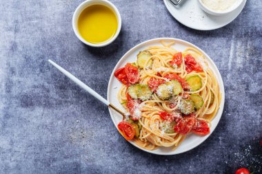 Geleneksel İtalyan makarnası, domates, kabak ve parmesan peyniri. Sağlıklı vejetaryen yemeği kavramı. Kopyalama alanı ile üstten aşağı görünüm