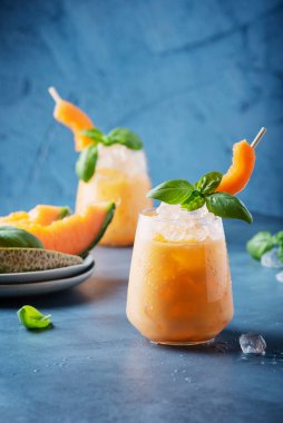 Bar konsepti. Tatlı yaz likörü, kavun, buz ve fesleğen, mavi arka planda. Metnin için kopyalama alanı olan seçici odak resmi