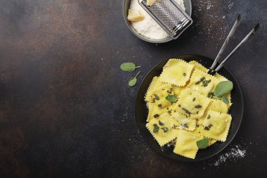 Koyu arkaplanda tereyağı, adaçayı ve peynirli geleneksel İtalyan mantısı. Kopya alanı olan İtalyan yemeği kavramı