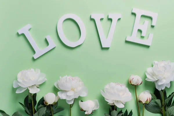 白色优雅的牡丹在绿色的背景上与木制的字母 贺卡的概念 爱情的概念 顶视图 — 图库照片