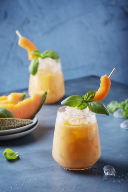 Bar konsepti. Tatlı yaz likörü, kavun, buz ve fesleğen, mavi arka planda. Metnin için kopyalama alanı olan seçici odak resmi