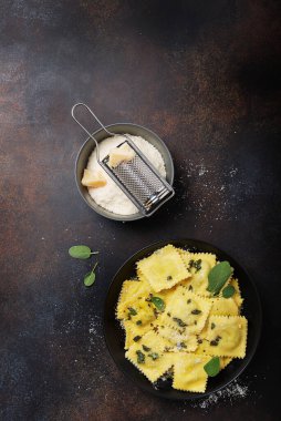 Koyu arkaplanda tereyağı, adaçayı ve peynirli geleneksel İtalyan mantısı. Kopya alanı olan İtalyan yemeği kavramı