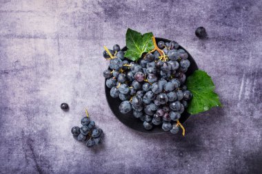 Koyu arkaplanda yeşil yapraklı siyah bir üzümün yukarıdan aşağı görünümü, metin için alanı kopyala