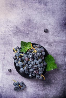 Koyu arkaplanda yeşil yapraklı siyah bir üzümün yukarıdan aşağı görünümü, metin için alanı kopyala