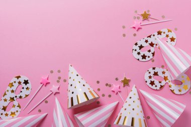 Doğum günü partisi konsepti. Parti şapkaları, maskeler ve pembe arka planda doğum günü mumları. Kopyalama alanı ile üstten aşağı görünüm