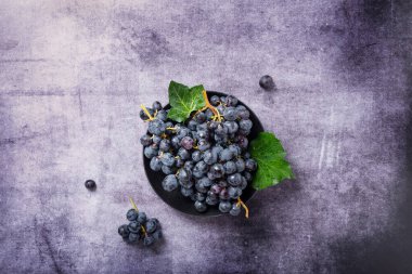 Koyu arkaplanda yeşil yapraklı siyah bir üzümün yukarıdan aşağı görünümü, metin için alanı kopyala