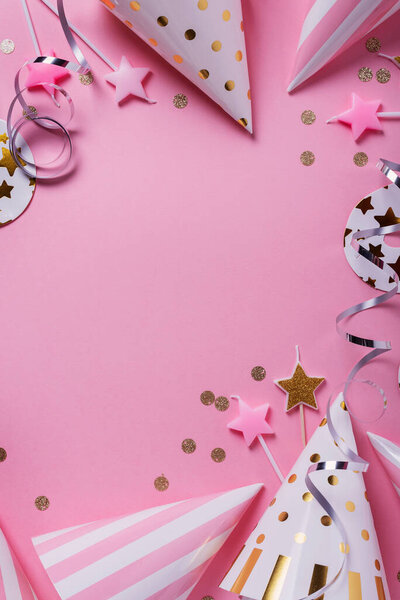 Концепция дня рождения. Шляпы для вечеринок, маски и свечи на розовом фоне. Вид сверху вниз с местом для копирования