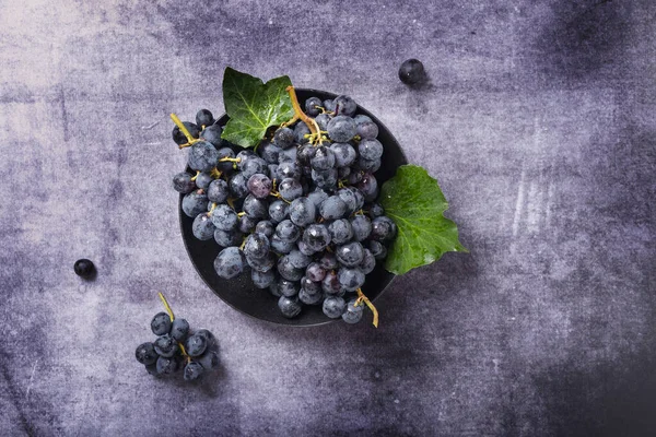 Koyu arkaplanda yeşil yapraklı siyah bir üzümün yukarıdan aşağı görünümü, metin için alanı kopyala