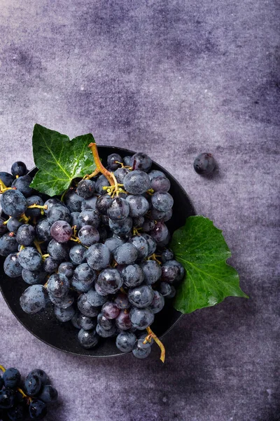 Koyu arkaplanda yeşil yapraklı siyah bir üzümün yukarıdan aşağı görünümü, metin için alanı kopyala