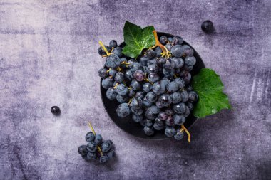 Koyu arkaplanda yeşil yapraklı siyah bir üzümün yukarıdan aşağı görünümü, metin için alanı kopyala