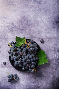 Koyu arkaplanda yeşil yapraklı siyah bir üzümün yukarıdan aşağı görünümü, metin için alanı kopyala