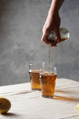 Bir bardağa siyah sıcak çay dolduran kadın, minimalizm tarzında seçici odak görüntüsü